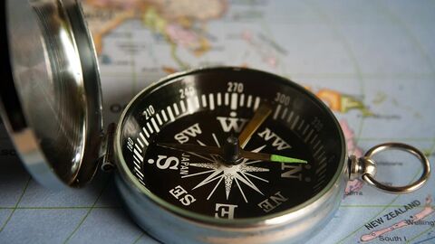 Magnetischer Kompass liegt aufgeklappt auf einer Landkarte.