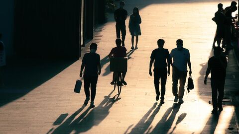Menschen im Gegenlicht spazieren über einen Platz.
